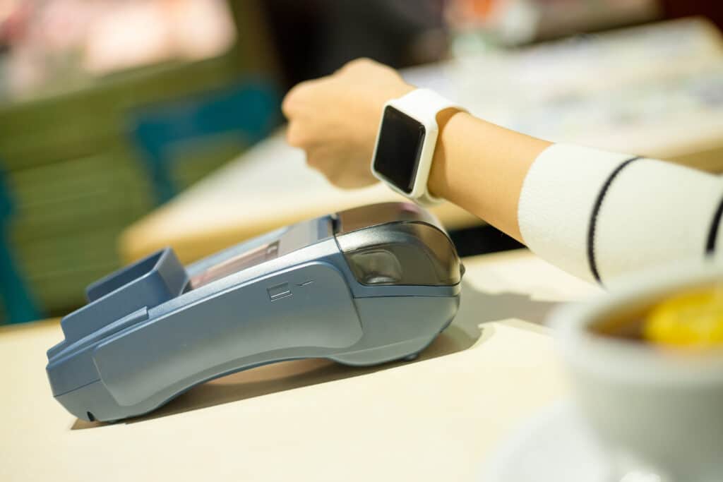 A person scanning a Smartwatch to RFID scanner device to pay a bill